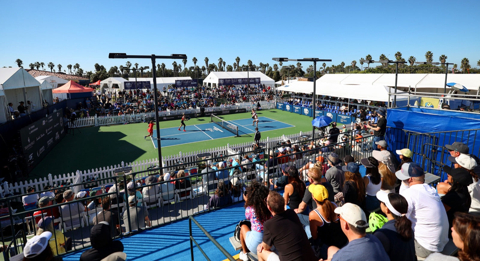 A crowd watching a pickleball match at a big outdoor event